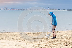 Guy walking dog on beach by sea