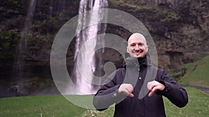 Guy on a waterfall shows a heart with his hands