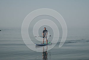 Guy in a wetsuit on a Board with an oar, rest on the sea