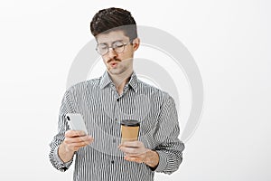 Guy whistling, seeing troubling message from boss. Portrait of indifferent handsome european male model with beard and photo