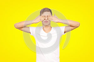 Guy in a white T-shirt closes his eyes, isolated on a yellow background