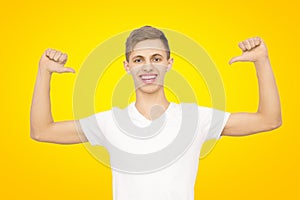 A guy in a white T-shirt with his hands up in the studio on a yellow background, isolate