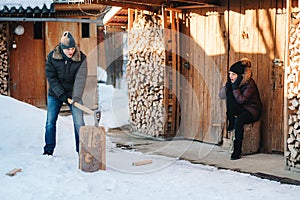 Guy in winter clothes chopping wood in the yard