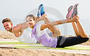 Guy and woman doing workout on beach by ocean