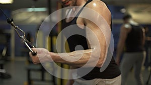 Guy working hard in gym doing brisk pull-downs with one arm, finishing exercise