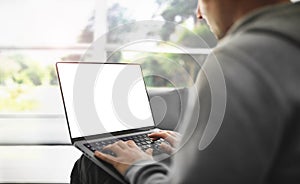 The guy is working on a laptop with a blank screen at home with a view of the park - a template for working from home.