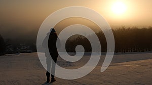 The guy young man looking at the sunrise in a frosty morning.