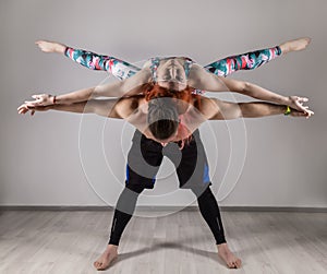 Guy and young woman doing strength exercises in yoga assanes. Acroyoga concept