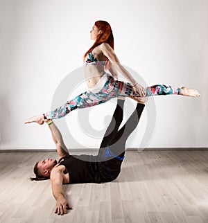 Guy and young woman doing strength exercises in yoga assanes. Acroyoga concept