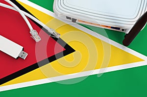 Guyana flag depicted on table with internet rj45 cable, wireless usb wifi adapter and router. Internet connection concept