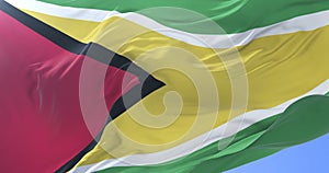 Guyana flag waving at wind in slow in blue sky, loop