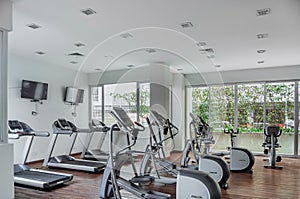 gym as an amenity within apartment towers, treadmill with televisions, exercise and ecliptic bikes, wood floors and photo