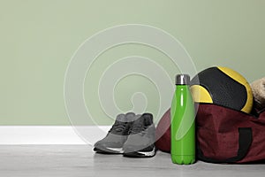 Gym bag and sports equipment on floor indoors, space for text