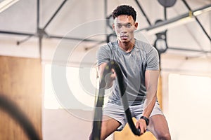 Gym battle ropes, training and black man athlete in a cardio, workout and sports exercise. Man in a wellness rope and