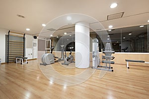 A gym with cardio equipment in the basement of an urban apartment building