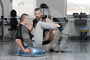 Gym Coach Helping Man On Bosu Abs Exercise