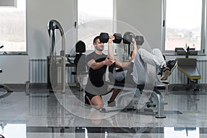 Gym Coach Helping Man On Chest Exercise