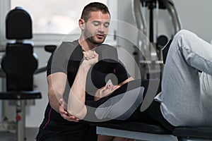 Gym Coach Helping Man On Chest Exercise