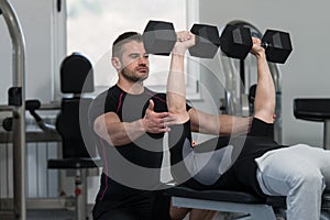 Gym Coach Helping Man On Chest Exercise