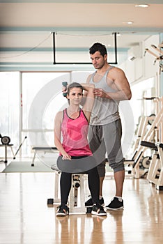 Gym Coach Helping Woman On Triceps Exercise