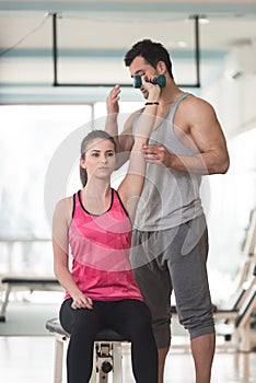 Gym Coach Helping Woman On Triceps Exercise
