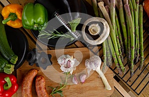 Gym dumbbells, vegetables and sausages for grill. Barbecue party composition, healthy diet choice concept.