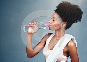 Gym, fitness and woman drinking water in studio for training, workout or intense cardio exercise on grey background