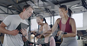 Gym instructor checking trainees progress and adjusting limit on exercise cycle machine for a stronger workout. Male