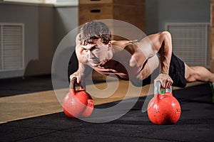 Gym man push-up strength pushup exercise with Kettlebell in a workout