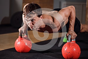 Gym man push-up strength pushup exercise with Kettlebell in a workout