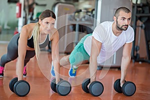 Gym man and woman push-up strength pushup with dumbbell in a workout