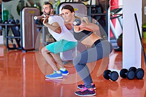 Gym man and woman push-up strength pushup with dumbbell in a workout