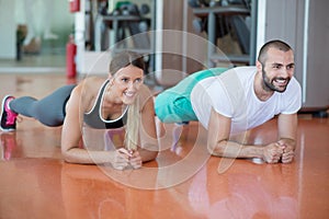 Gym man and woman push-up strength pushup with dumbbell in a workout