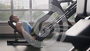 In the gym - muscular man exercising on leg press machine