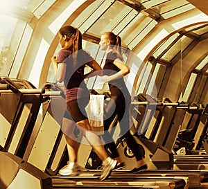 Gym shot - two young women running on machines, treadmill