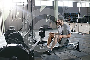 Gym. Sports Man Training On Rowing Machine