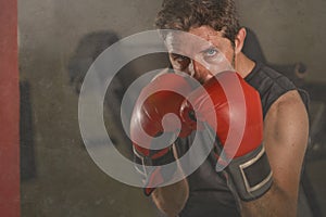 Gym workout portrait of attractive and fierce looking boxer man 30s to 40s in boxing gloves training at fitness club punching