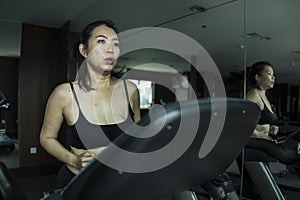 Gym workout portrait of young beautiful and sporty Asian Chinese woman running at fitness club jogging in treadmill training in