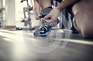 Gym workout routine man tying running shoes shoelace preparing for a jog or physical exercise