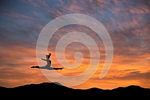 Gymnast doing the splits jump in sunset