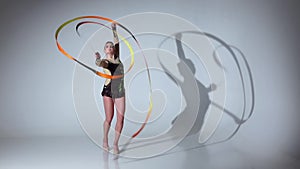 Gymnast gracefully move with a ribbon in his hands. White background. Slow motion