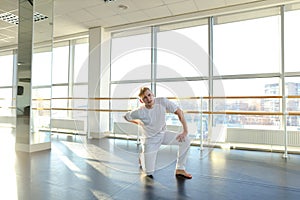 Gymnast in sportswear training near ballet barre in sport gym