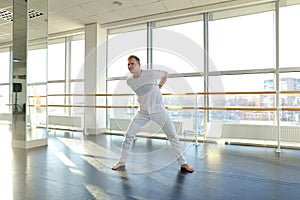 Gymnast in sportswear training near ballet barre in sport gym