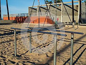 Gymnastics and exercise parallel bars on beach in outdoor gym with men exercising in the back