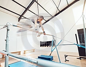 Gymnastics, olympics and sports with a gymnast swinging on a horizontal bar inside of a gym for fitness, training and