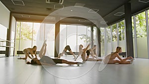 Gymnastics studio. Group of young women stretching their bodies before dance rehearsal, tracking shot, slow motion