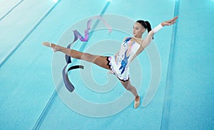 Gymnastics, woman is dancing with ribbon and performance, flexibility with professional athlete in gym and top view