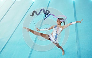 Gymnastics, woman with ribbon for dance and sport performance, flexibility with professional athlete in gym and top view