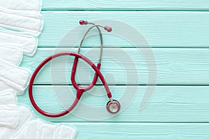 Menstruation calendar concept with sanitary pads, stethoscope on mint green wooden background top view mockup photo