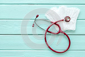 Menstruation calendar concept with sanitary pads, stethoscope on mint green wooden background top view mockup photo